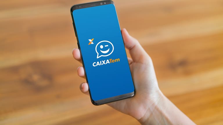 Homem segurando aparelho celular, na tela mostra app caixa tem