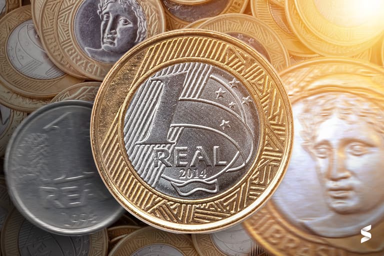 Imagem de várias moedas de 1 real, destacando a moeda de 2014 com possibilidade de erro de cunhagem.