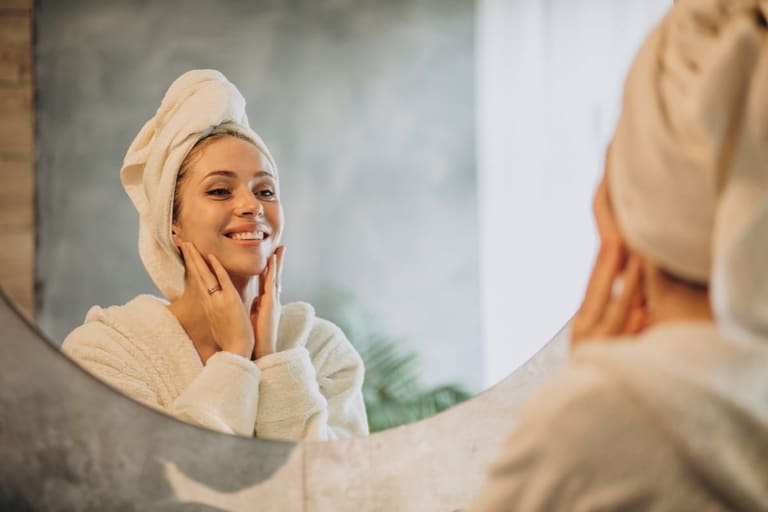 Mulher satisfeita observando resultados de skincare no espelho após rotina personalizada de cuidados