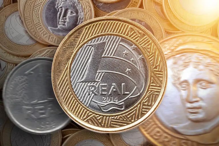 Moeda de 1 real brasileira de 2014 entre outras moedas, com detalhes em dourado e prata