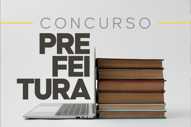 Computador aberto ao lado de pilha de livros com texto sobre concurso prefeitura