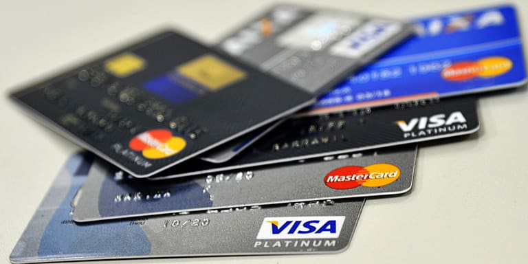 Pilha de cartões de crédito Visa Platinum e MasterCard Platinum em superfície branca