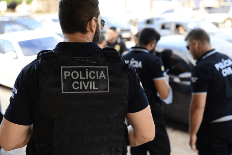Concursos Polícia Civil Policiais civis com coletes e uniformes em operação junto a carros estacionados na rua