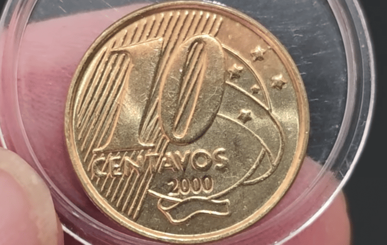 Close de uma moeda de 10 centavos de Real do ano 2000, protegida por uma cápsula de acrílico transparente, mostrando o número 10 e o ano de cunhagem com clareza.