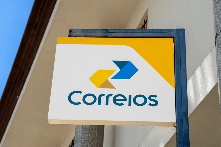 Placa dos Correios com logotipo amarelo e azul fixada na fachada de prédio