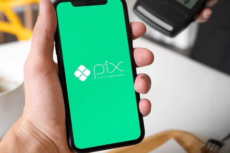 Celular exibindo tela do Pix enquanto usuário segura o aparelho para pagamento digital.