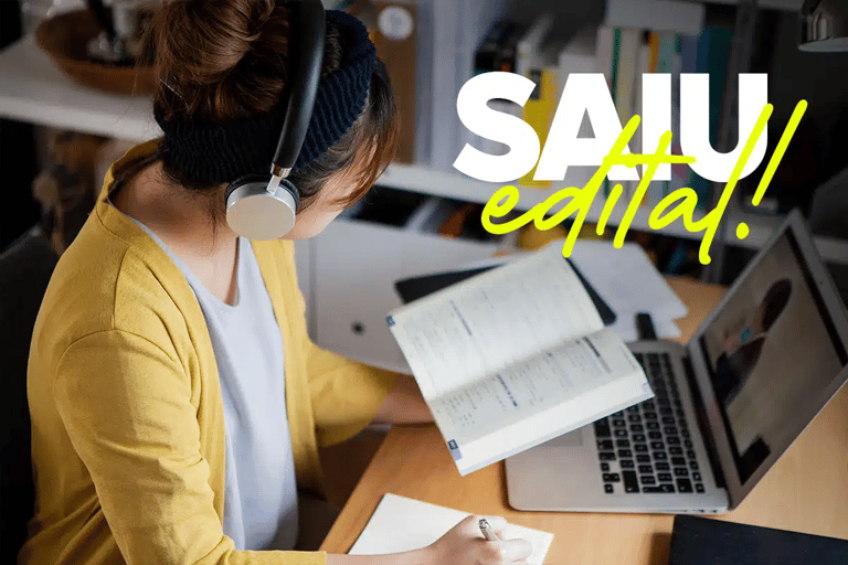 Jovem estudando com fone de ouvido, livro aberto e notebook com texto Saiu Edital em destaque