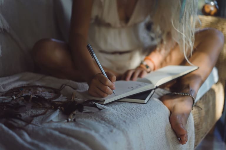 Mulher sentada escrevendo em caderno antes de dormir como técnica para acalmar a mente e dormir mais rápido