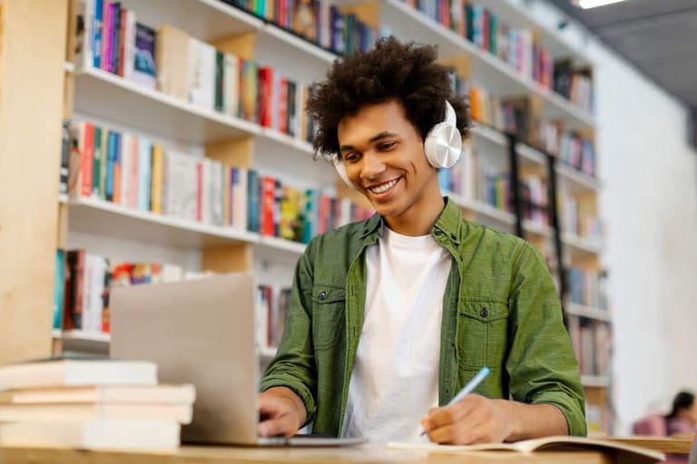 Idiomas mais fáceis para brasileiros aprenderem. Estudante usando notebook e fones de ouvido enquanto aprende idiomas em uma biblioteca.