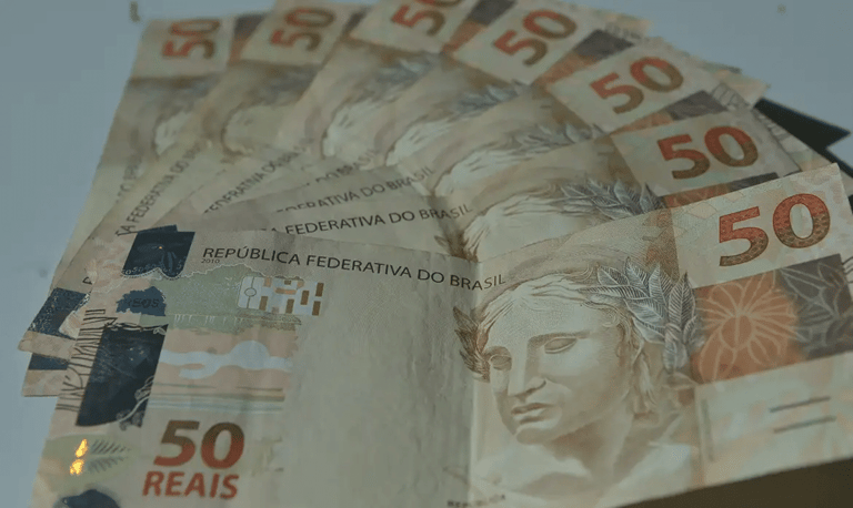 Conjunto de cédulas de cinquenta reais dispostas em leque sobre superfície clara