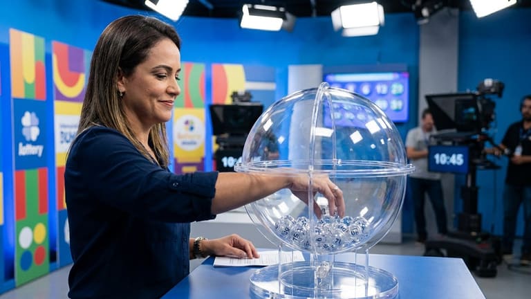 Apresentadora retira bola de globo transparente durante extração da Loteria dos Sonhos em estúdio de TV