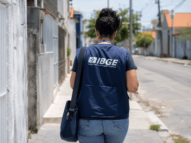 Profissional do IBGE caminha pela rua durante trabalho de campo.