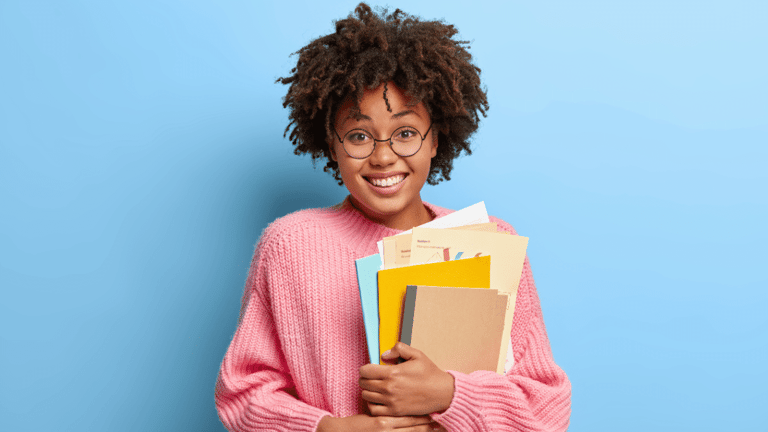 Jovem segurando livros e documentos para estudos de concursos públicos.