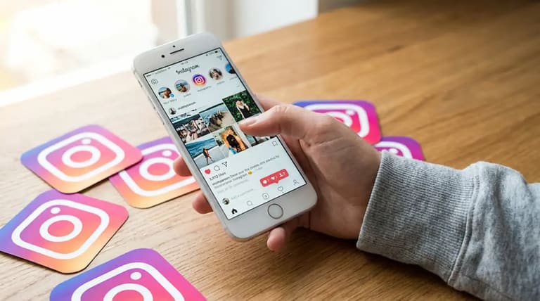 Pessoa usando o Instagram em um celular sobre uma mesa com ícones da rede social, em contexto de debate sobre localização em tempo real e proteção de dados.