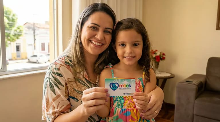 Mãe sorrindo com filha segurando cartão do Programa Mães de Pernambuco.