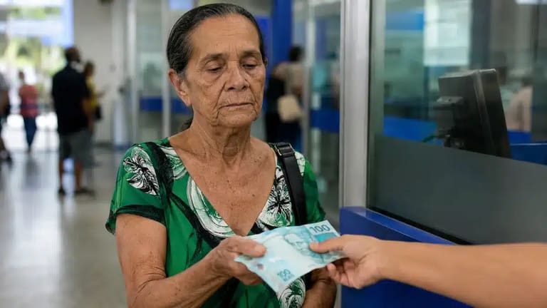Mulher idosa recebendo pagamento do INSS em agência bancária brasileira