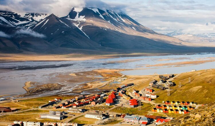 A cidade onde é proibido morrer: Conheça o lugar mais bizarro do mundo onde as leis desafiam a lógica 1 Vista panorâmica de Longyearbyen, Noruega, com casas coloridas, montanhas nevadas e rios congelados ao fundo.