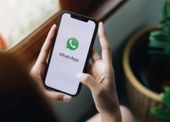 Pessoa segurando celular com o logo do WhatsApp na tela, mostrando a funcionalidade para liberar espaço sem apagar fotos.
