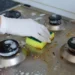 Pessoa limpando gordura do fogão com esponja e luvas