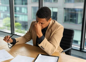 Profissional com expressão de frustração em um escritório, refletindo sobre seus erros no trabalho