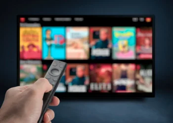 Tela de TV exibindo várias opções de filmes e séries de streaming, com controle remoto em mãos, simbolizando a comparação entre os serviços de Netflix, Max e Prime.