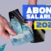 Consulta ao Abono Salarial está disponível; veja como realizar 13 Mãos colocando notas de cem reais em carteira preta ao lado de texto sobre abono salarial 2026.