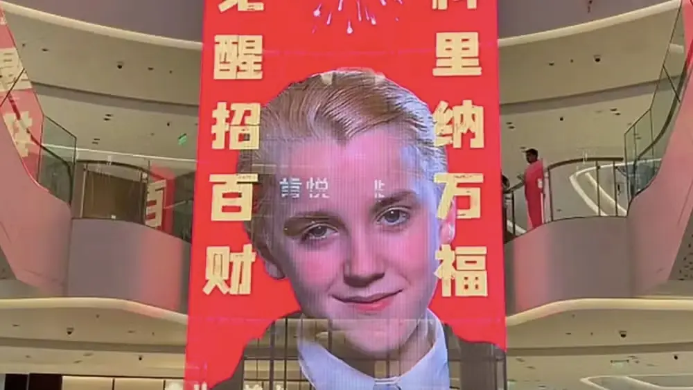 Personagem de Harry Potter ganha destaque na cultura chinesa como mascote de festa; confira 2 Painel publicitário em shopping chinês celebrando o Ano Novo Lunar com a imagem de Tom Felton como Draco Malfoy, personagem de Harry Potter.