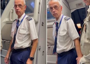 Homem com uniforme de piloto é abordado por policial dentro de avião, expressão surpresa