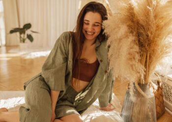 Mulher sorridente usando conjunto de linho verde em ambiente acolhedor com decoração natural