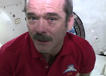 Astronauta de bigode com lágrima escorrendo dentro de estação espacial internacional