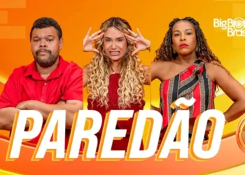 Três participantes em frente a fundo laranja, com expressões tensas e palavra paredão destacada.