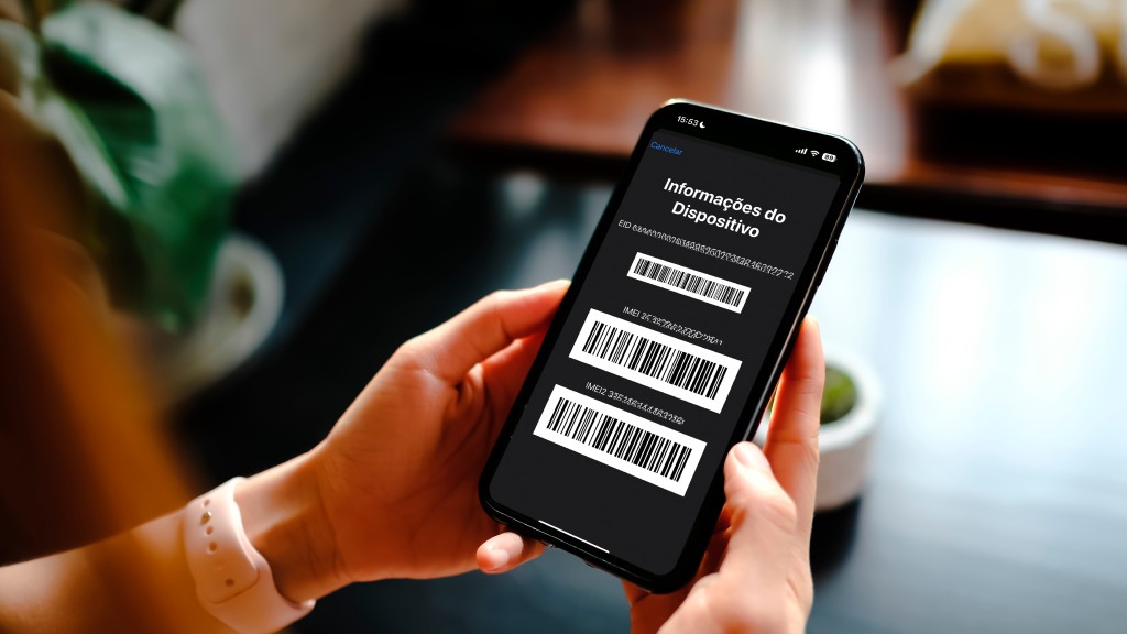 Saiba o que acontece se você digitar o código *#06# no seu celular agora 2 Pessoa segurando smartphone exibindo IMEI e códigos de barras na tela