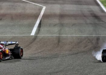 Visão ampla de dois carros de Fórmula 1, um da Ferrari e outro da McLaren, acelerando na reta principal do circuito de Sakhir durante os testes de pré-temporada.