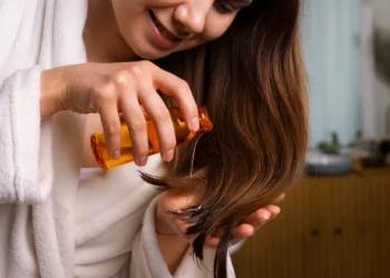 Cuidado: O ingrediente 'natural' que você está passando no cabelo e que pode estar destruindo os fios 6 Mulher aplicando óleo natural no cabelo e riscos escondidos.