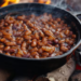 Panela de ferro com feijão cozinhando sobre fogo alto em lenha com chamas ao redor