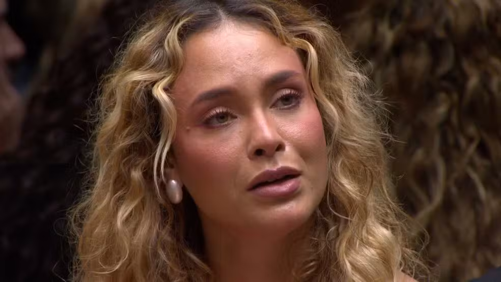 BBB 26: Quem foi o eliminado do paredão na última terça (10)? 2 Mulher loira de cabelos cacheados, usando brinco grande, com expressão emocionada e olhar levemente marejado.