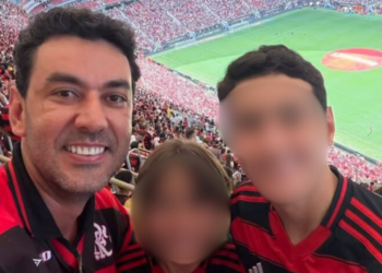 Três torcedores sorrindo com camisas do Flamengo em arquibancada de estádio