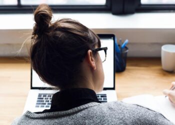 female-taking-notes-and-browsing-laptop