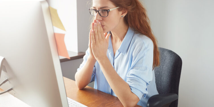 Portrait of young female writer thinking on text for a new book via PC while sitting in co-working space, pretty student girl busy working on course-work with concentrated expression.