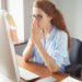 Portrait of young female writer thinking on text for a new book via PC while sitting in co-working space, pretty student girl busy working on course-work with concentrated expression.