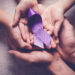 Adult and child hands holding purple ribbons, Alzheimer's disease, Pancreatic cancer, Epilepsy awareness, world cancer day