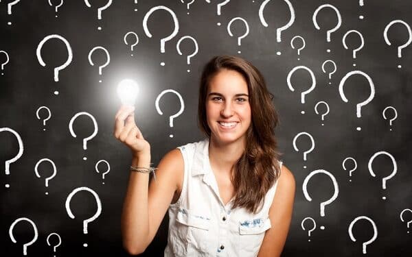 young woman holding a lightbulb with interrogation symbols