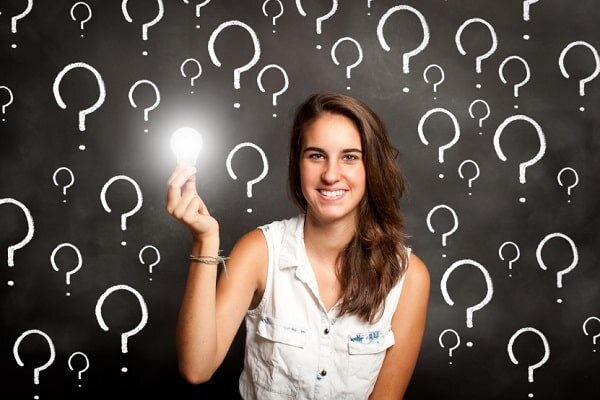 young woman holding a lightbulb with interrogation symbols