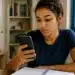 Jovem estudante consulta o celular para verificar informações sobre o cartão de confirmação do Encceja 2026