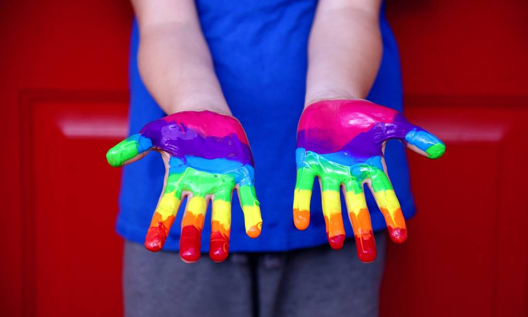 Mãos de criança pintadas de cores do arco-íris, símbolo LGBTQIA+