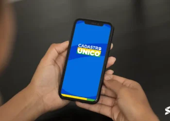 Pessoa segurando um celular com o logo do Cadúnico na tela