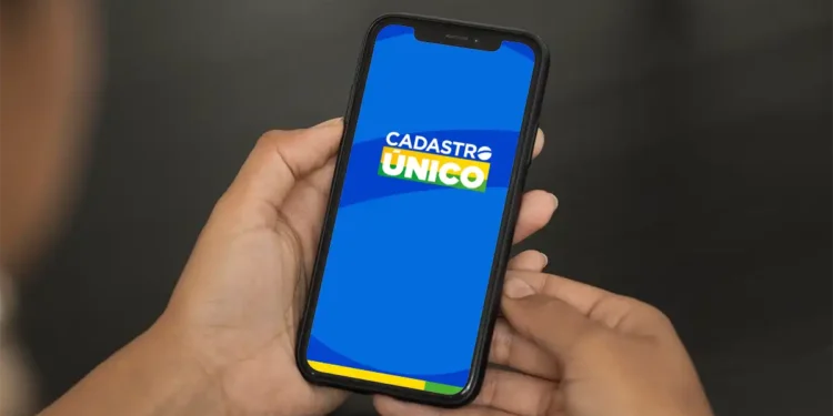 Pessoa segurando um celular com o logo do Cadúnico na tela
