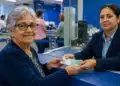 Idosa recebendo dinheiro de uma atendente em agência bancária, representando o pagamento de benefícios do INSS em julho de 2026.
