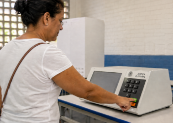 Eleitora utiliza urna eletrônica em local de votação, em referência ao voto em trânsito nas Eleições 2026.