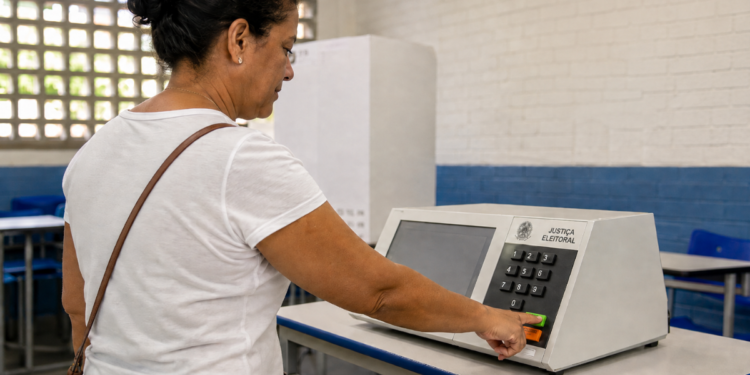 Eleitora utiliza urna eletrônica em local de votação, em referência ao voto em trânsito nas Eleições 2026.